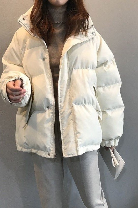 Cream puffer coat over a gray turtleneck, front view