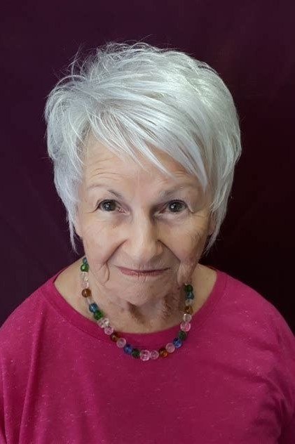 Neat white pixie haircut for women over 60, dark red background