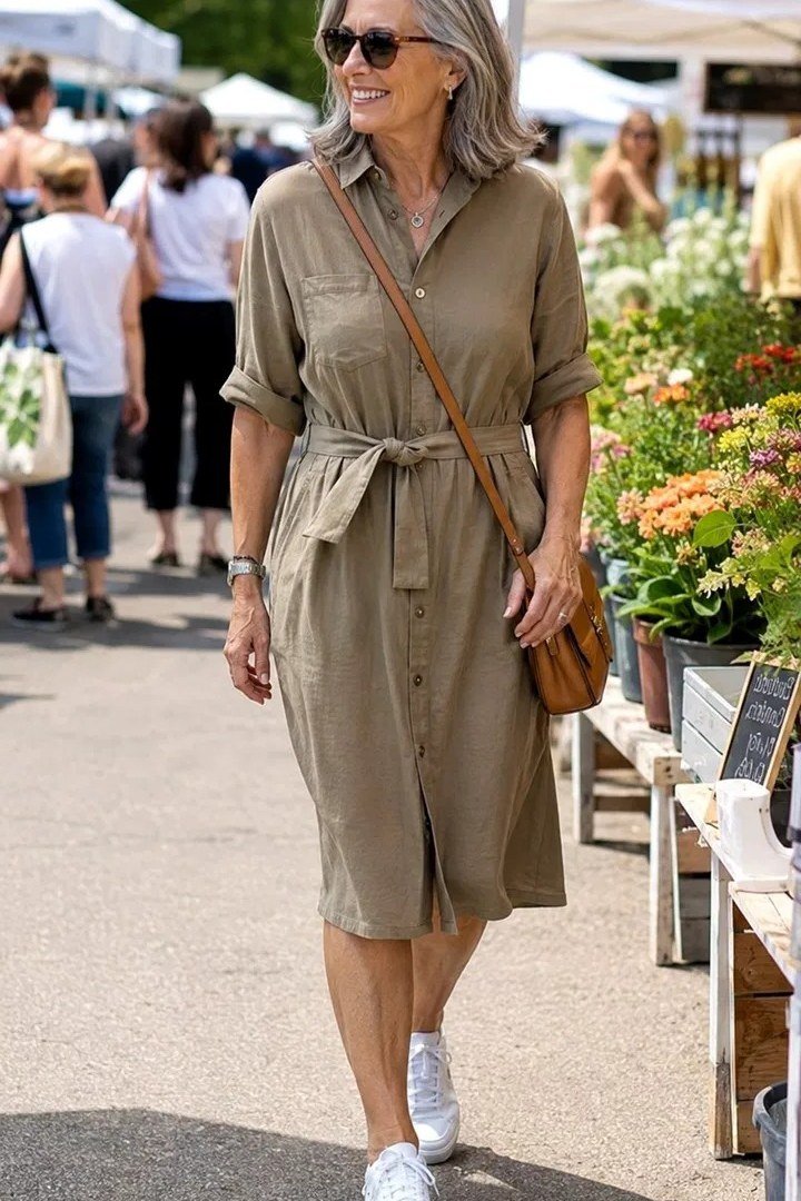 Khaki safari shirt dress for women over 60: tie waist and chest pockets with white sneakers and a tan crossbody