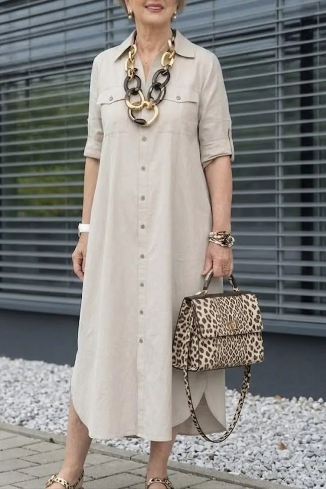 Cream maxi shirt dress for women over 60: soft cream with long sleeves, a chunky chain necklace and leopard bag