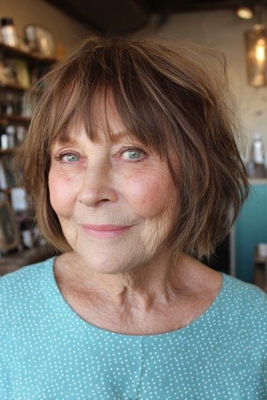 Auburn-brown shaggy bob with bangs on a woman over 60 in front view