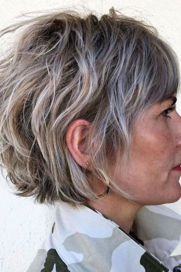 Shaggy pixie bob hairstyle for women over 60: silver-grey shaggy pixie bob, airy texture, side profile, older woman