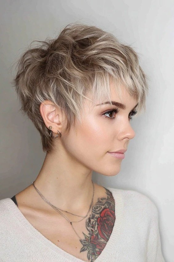 Shaggy pixie bob hairstyle for women over 60: silver-blonde textured pixie bob, piecey crown, younger woman, side 3/4 view