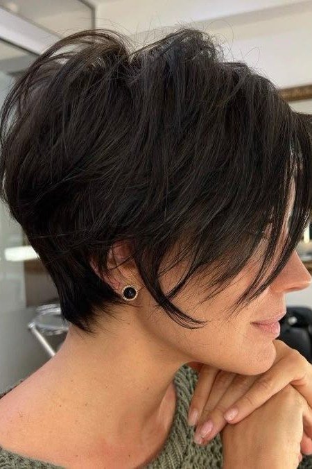 Shaggy pixie bob hairstyle for women over 60: black asymmetric shaggy pixie bob, sharp angled fringe, younger woman, side view