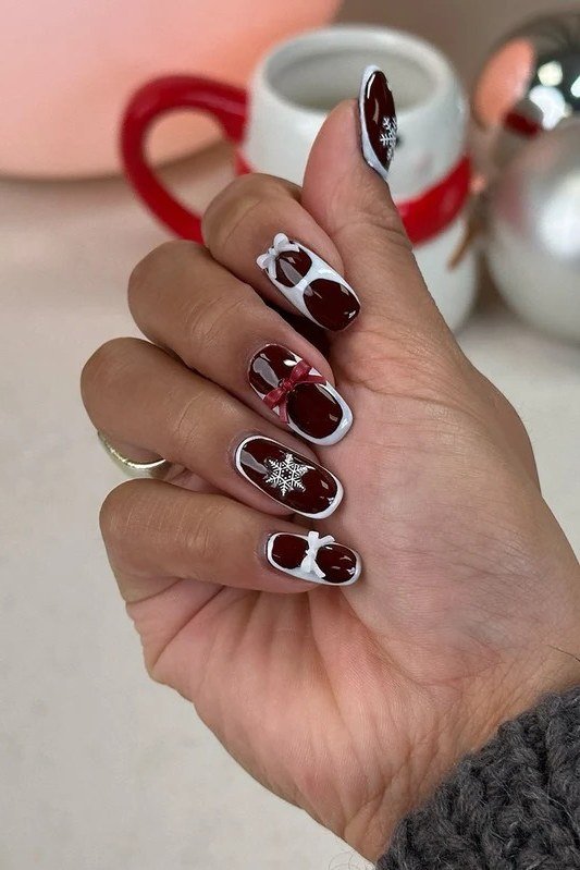 Dark moody nails with pale snowflake nail art, striking winter manicure design