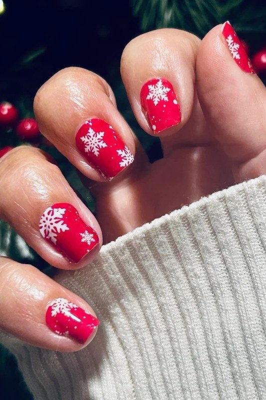 Bright red nails with white snowflake nail art, cheerful classic Christmas manicure