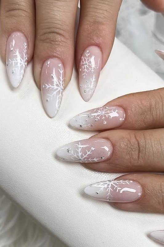 Pink ombre nails with white snowflakes on mature hands, soft baby-boomer winter look