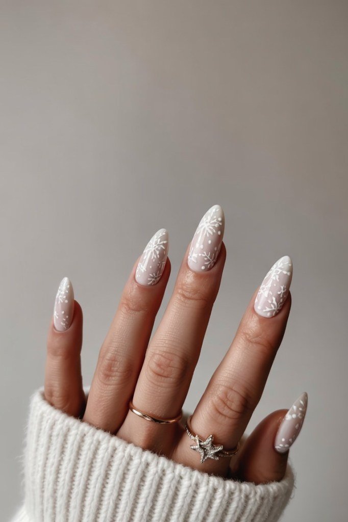 Warm nude nails with fine glitter and white snowflakes, understated glam winter manicure