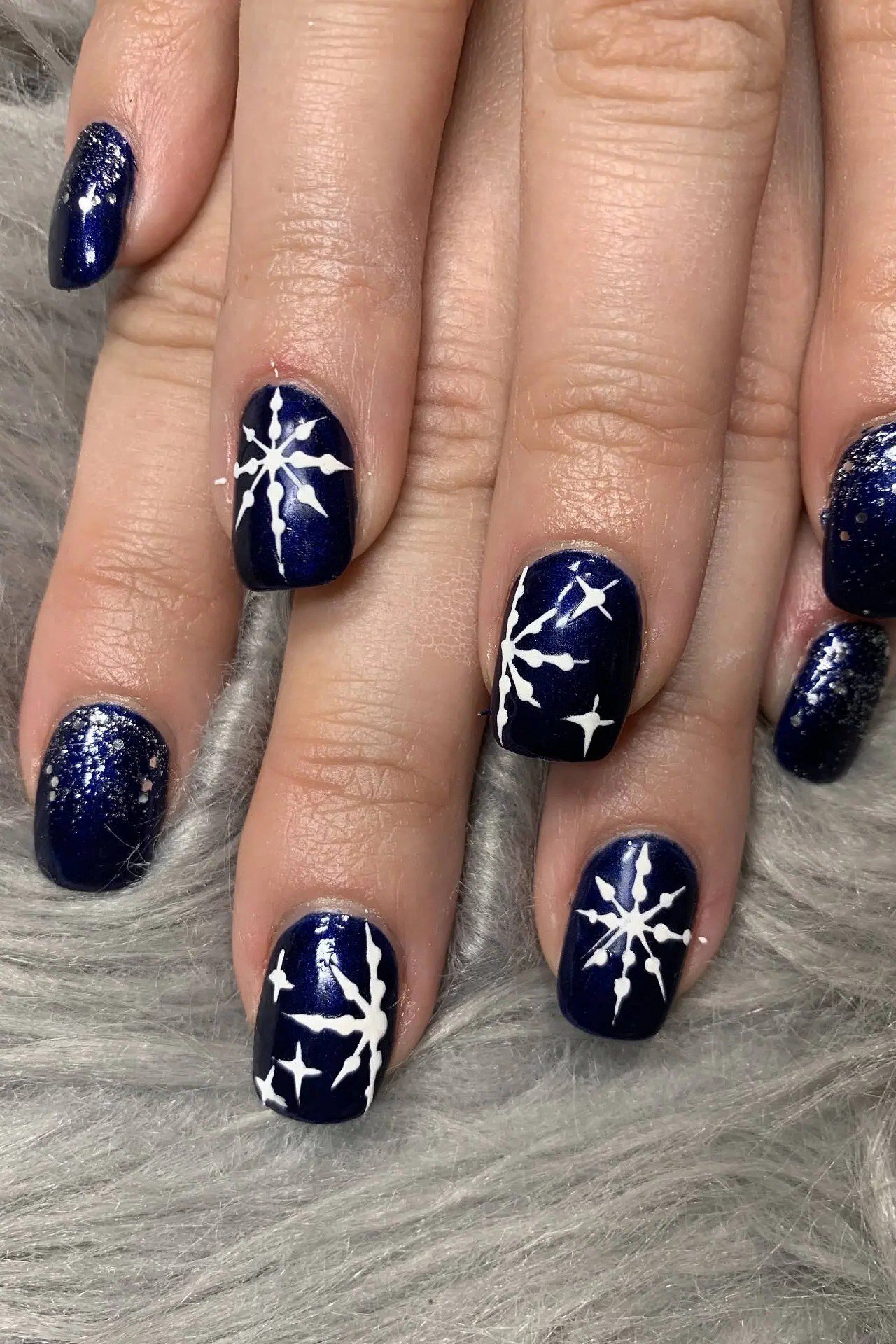 Glossy navy nails with delicate white snowflakes, timeless winter night manicure