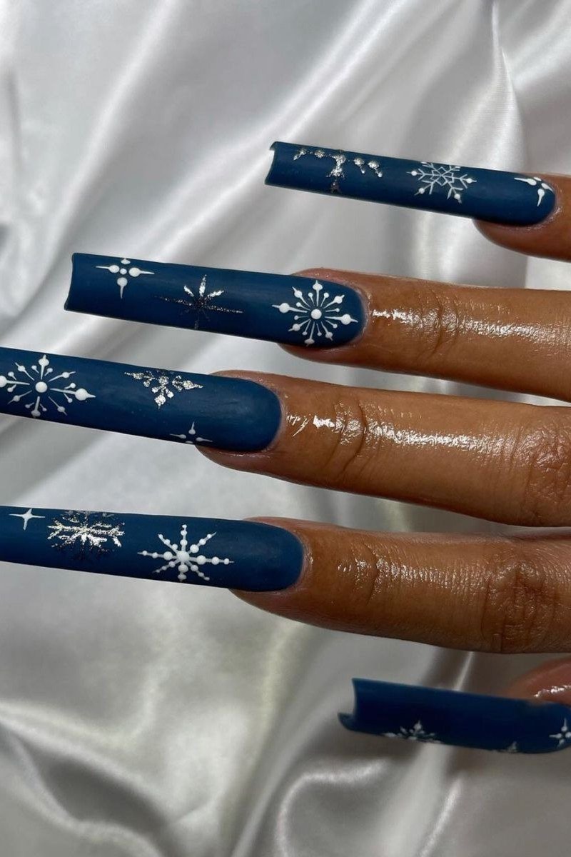 Navy stiletto nails with white snowflakes, dramatic pointed winter nail art