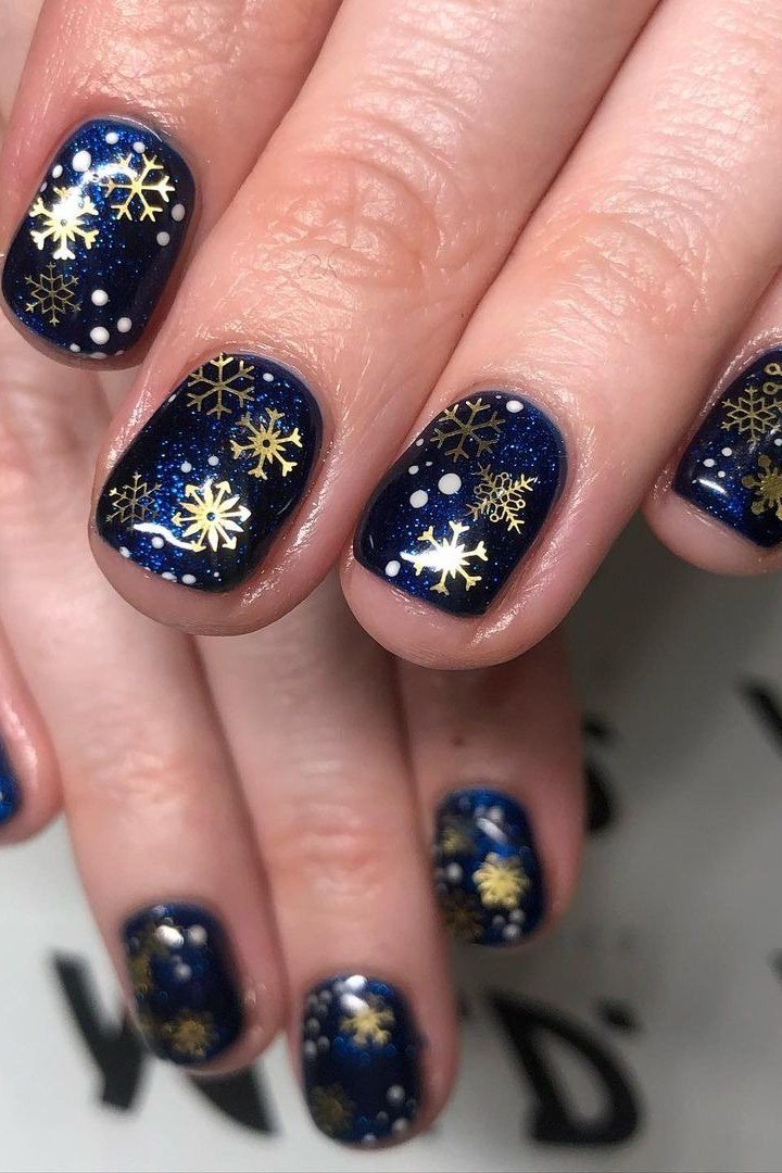 Navy nails with gold snowflake nail art, luxurious holiday winter manicure