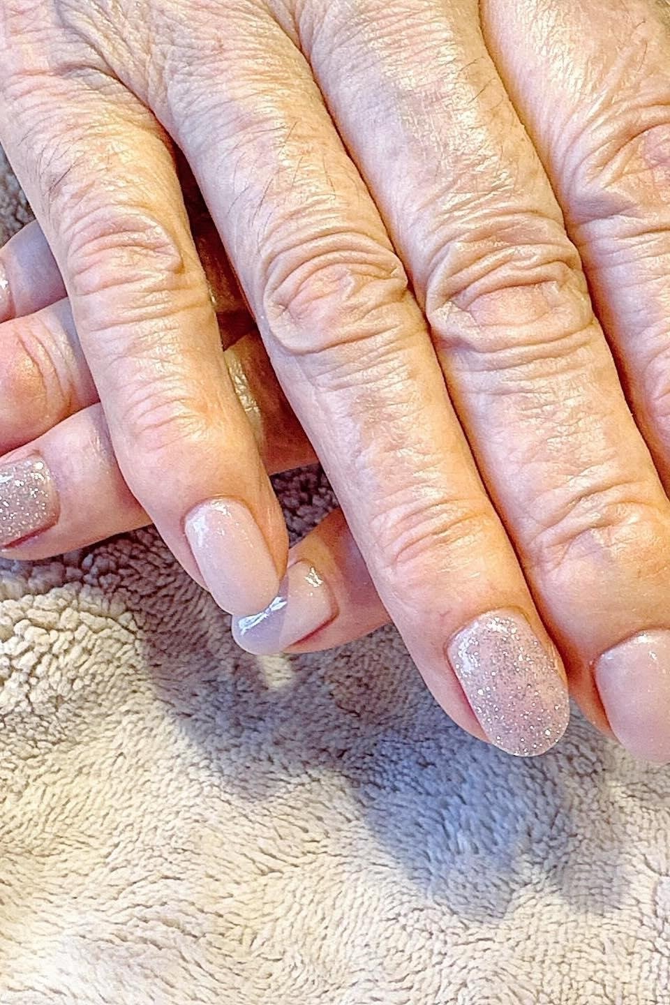 Pale pink nails with glitter accent nail on mature hands