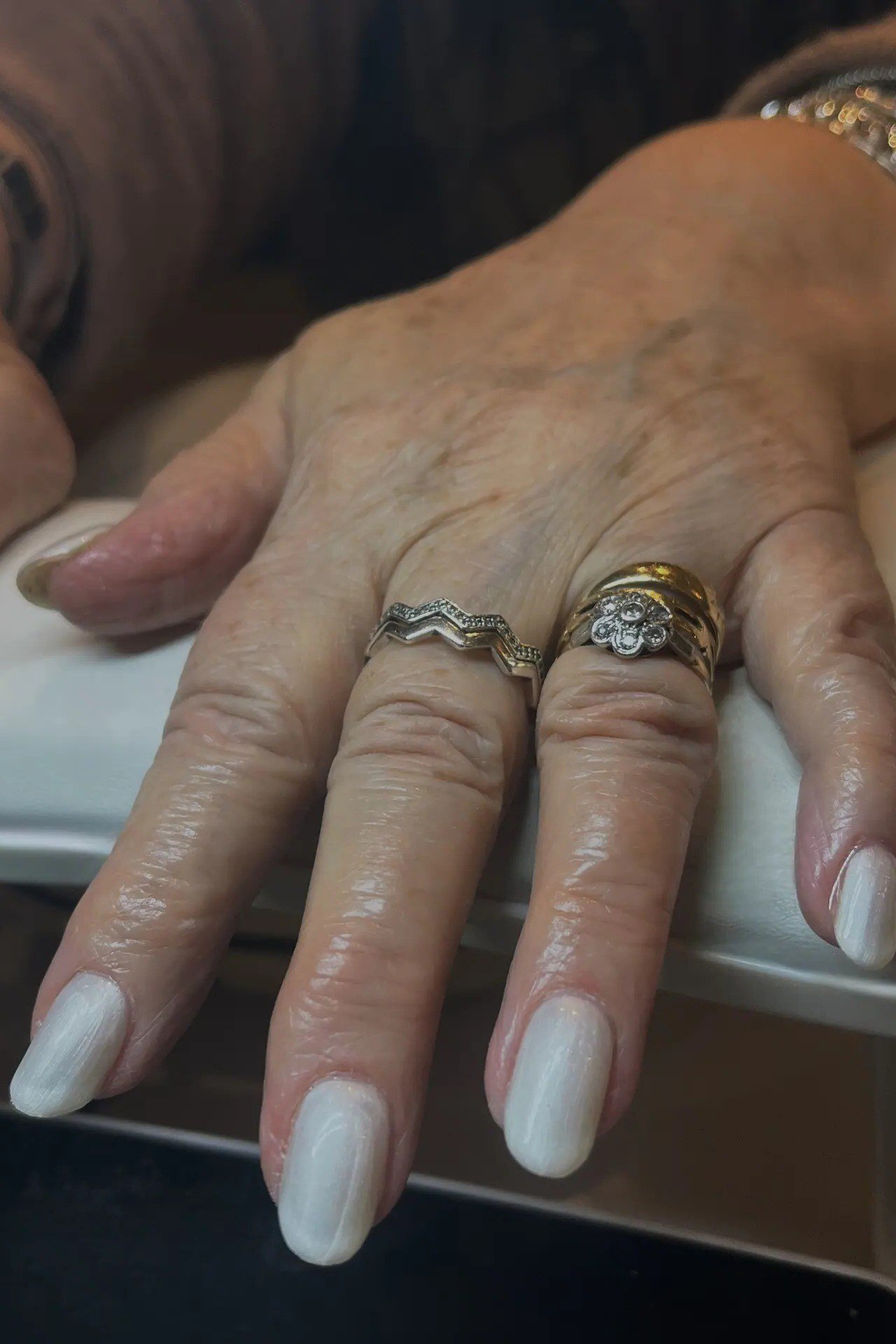 White nail polish with rings on mature hands
