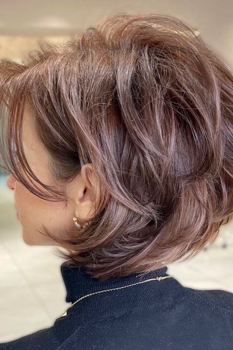 Dusty rose tinted stacked bob haircut for women over 60, side view