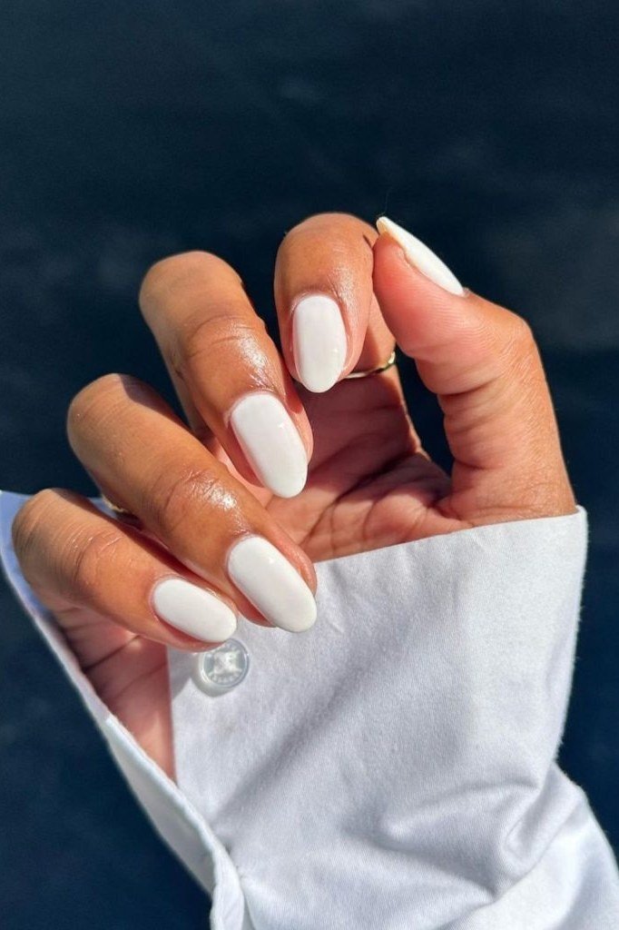 White oval nails on dark skin with white shirt sleeve, elegant summer white nails