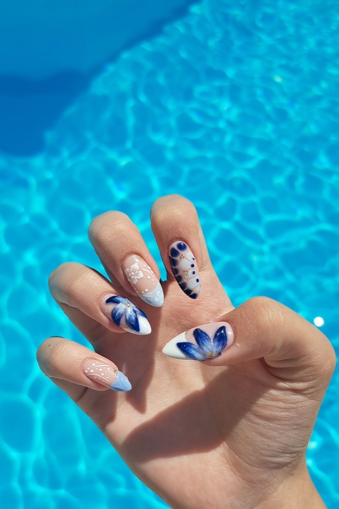 Blue and white hibiscus floral nail art on almond nails by the pool, summer vacation nails