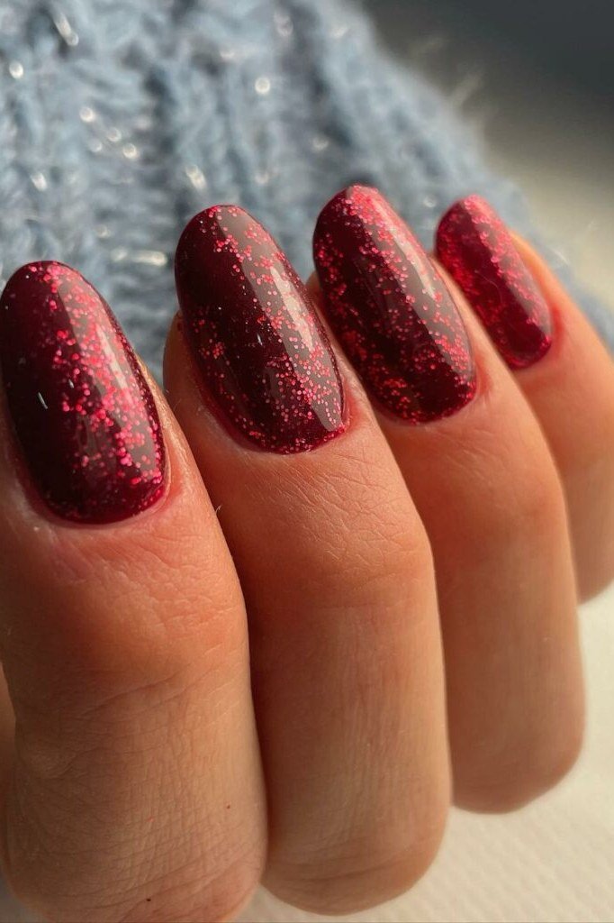 Deep burgundy nails with red glitter overlay on almond shape, glam summer nails