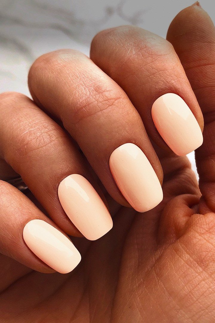 Peachy nude short nails with glossy finish on medium skin tone, everyday summer nails