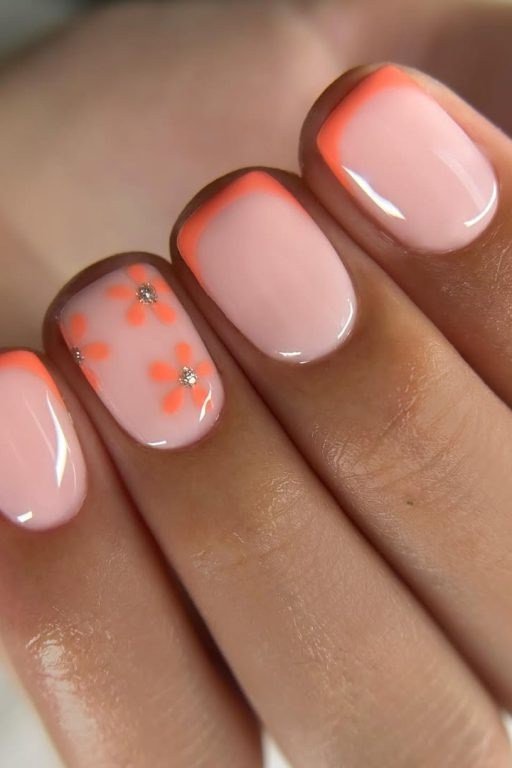 Nude nails with coral French tips and orange daisy nail art with crystal center