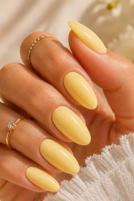 Butter yellow medium almond nails with glossy finish, soft pastel summer yellow nails