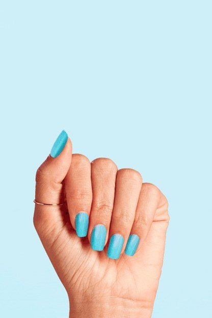 Turquoise blue medium almond nails with glossy finish on pale blue background