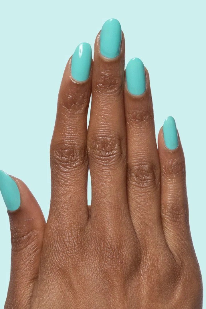 Solid mint green oval nails with glossy finish on dark skin tone, fresh summer nails
