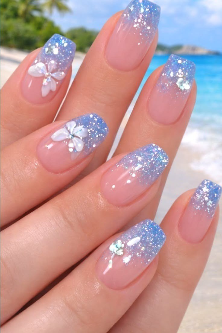 Nude nails with blue glitter tips and white flower nail art at the beach, floral summer nails