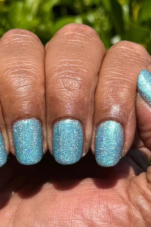 Aqua blue glitter short nails with full sparkle coverage on dark skin, dazzling summer nails