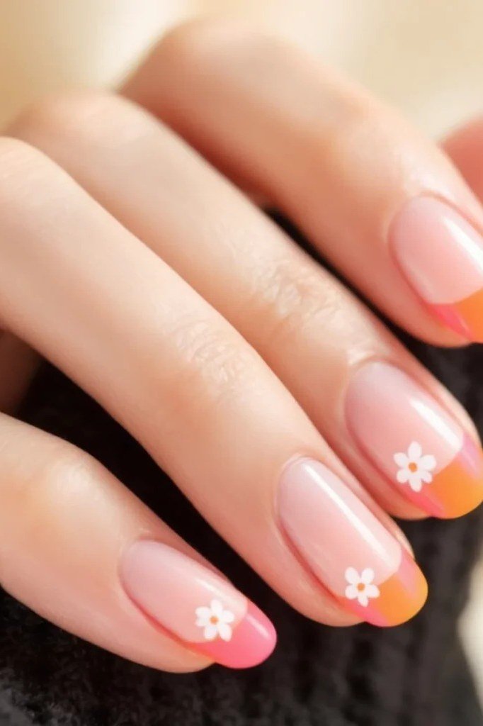 Nude almond nails with orange and pink French tips and white daisy nail art, cheerful summer nails