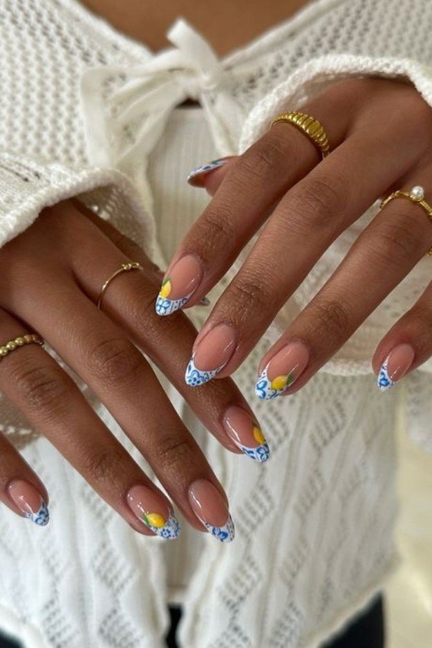 Nude almond nails with blue and white tile pattern French tips and lemon nail art