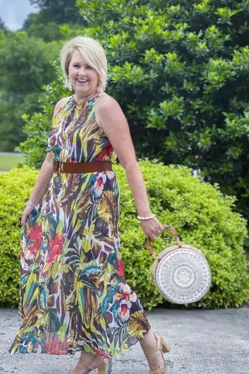 Older woman wearing tropical print maxi sundress, round straw bag, garden - summer sundresses for women over 60