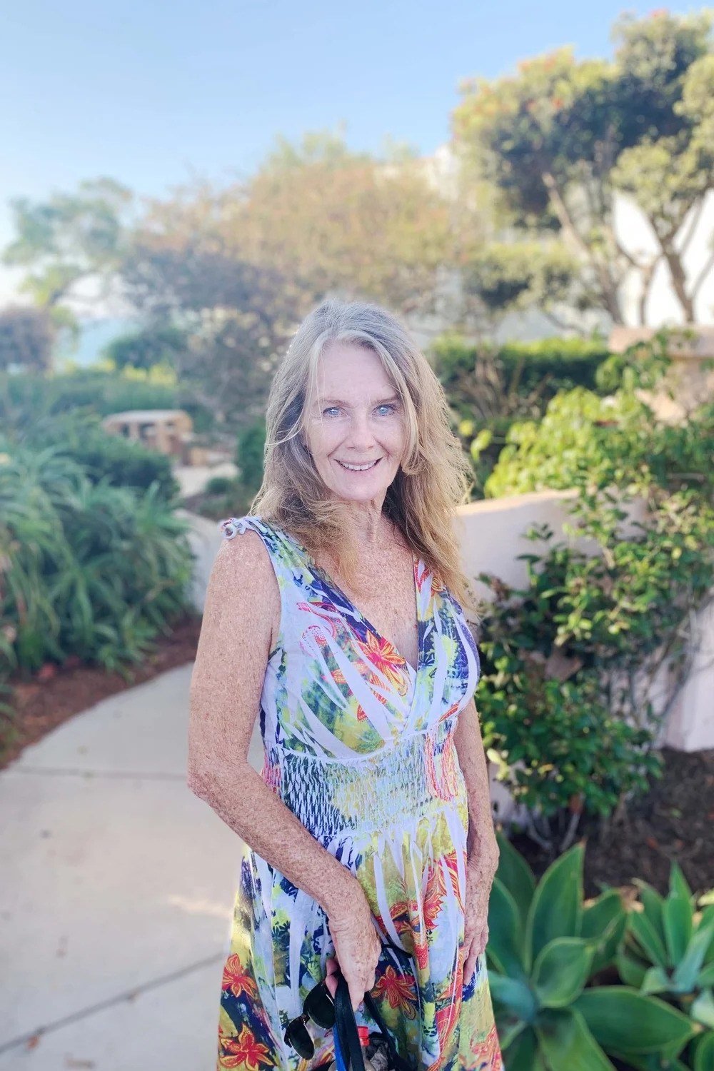 Older woman wearing watercolor floral maxi sundress on path - summer sundresses for women over 60