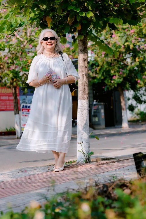 Older woman wearing white eyelet midi dress on street - summer sundresses for women over 60
