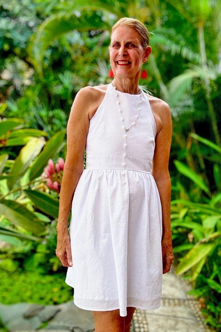Older woman wearing white halter mini dress in garden - summer sundresses for women over 60