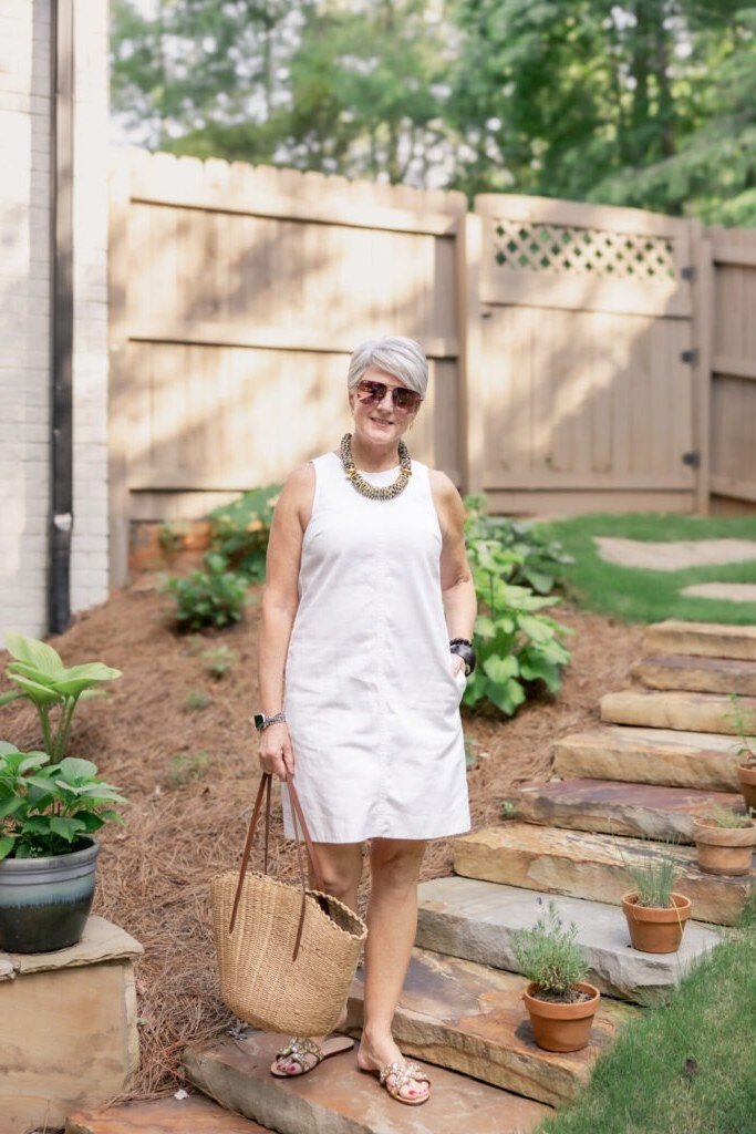 Older woman wearing white sheath dress on garden stairs - summer sundresses for women over 60
