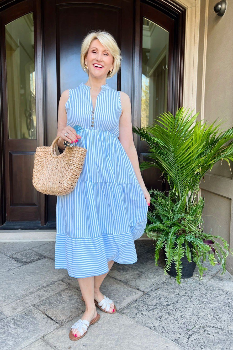 Older woman wearing blue striped sundress with straw bag, doorway - summer sundresses for women over 60