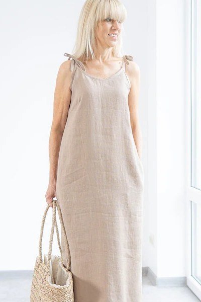 Older woman wearing beige linen maxi dress with straw tote - summer sundresses for women over 60