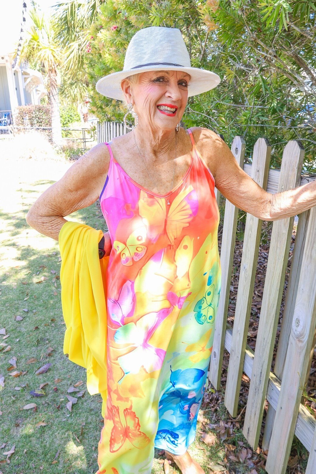 Older woman wearing rainbow tie-dye maxi sundress, white hat - summer sundresses for women over 60