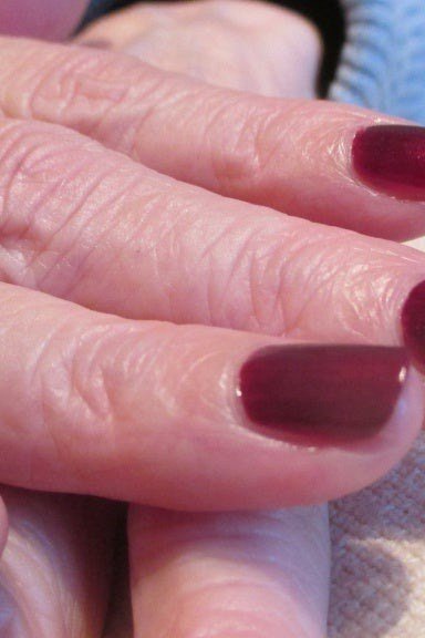 Deep wine red nail polish on older hands
