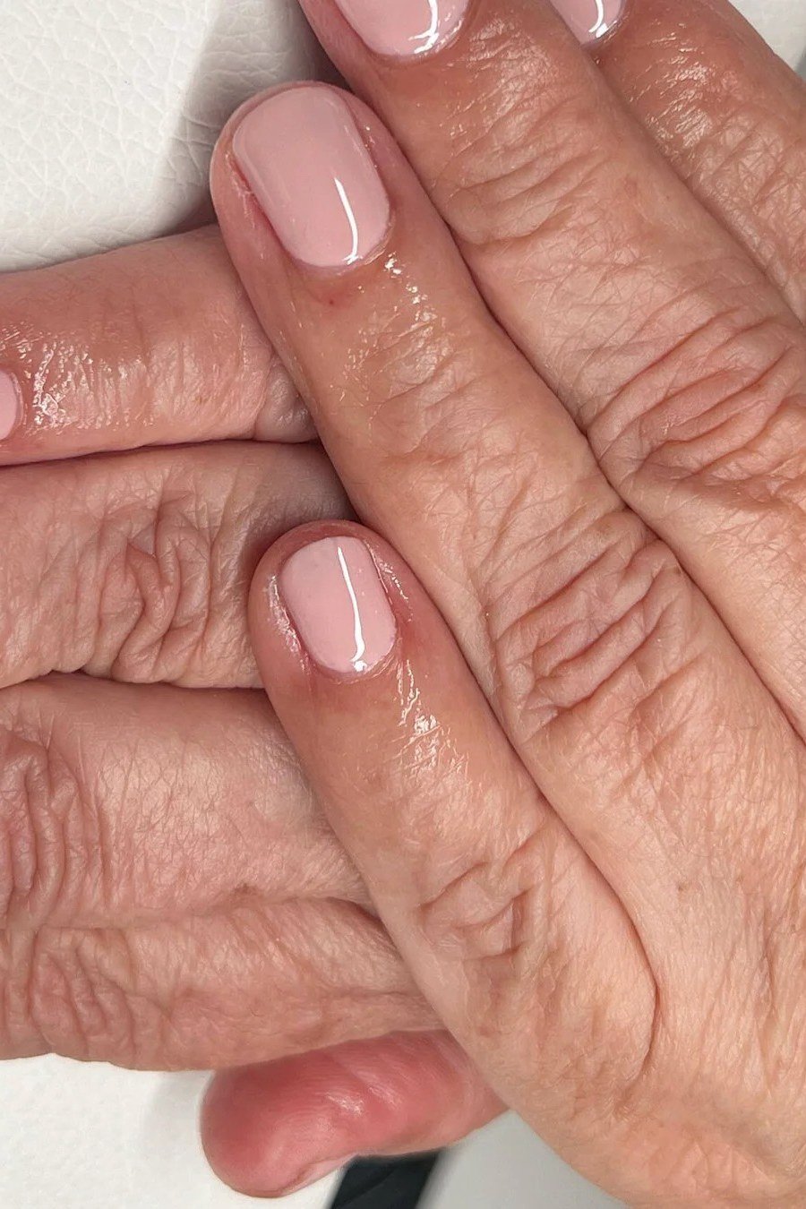 Sheer blush pink nail polish on mature hands