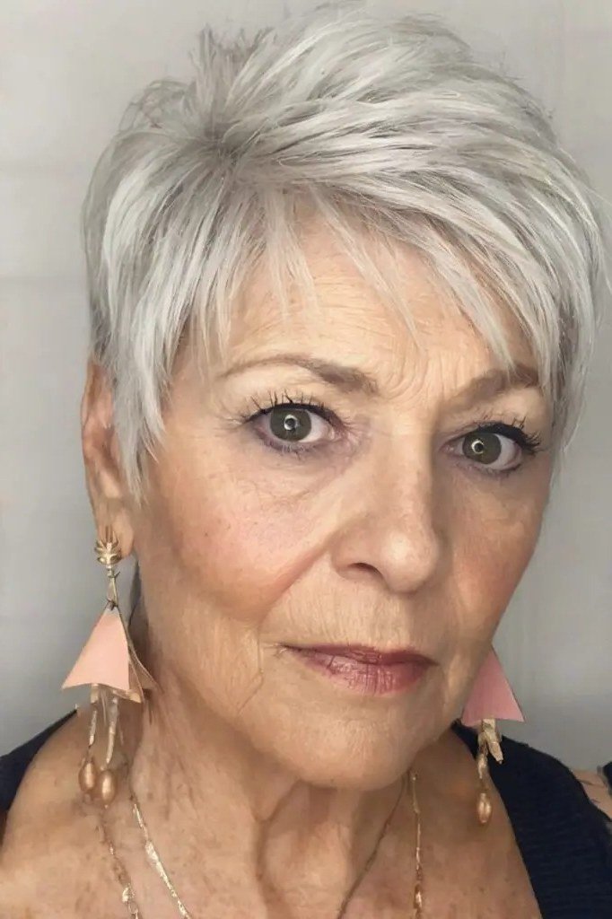 White pixie haircut for women over 60 with pink earrings