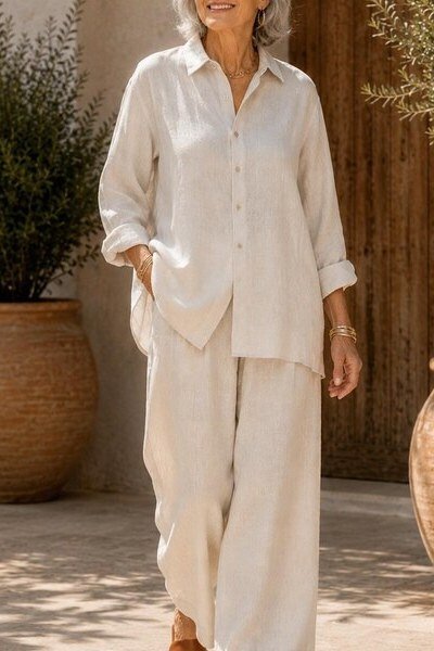 Older woman wearing cream linen shirt and wide-leg linen pants, sunny courtyard, a timeless casual outfit for women over 60.