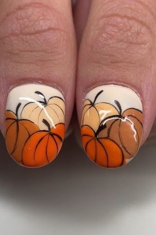 Hand-painted pumpkin nail art on white accent nails