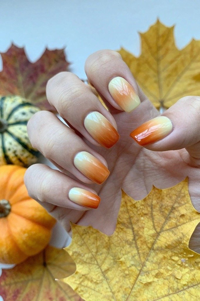 Orange ombre nails fading from peach to pumpkin