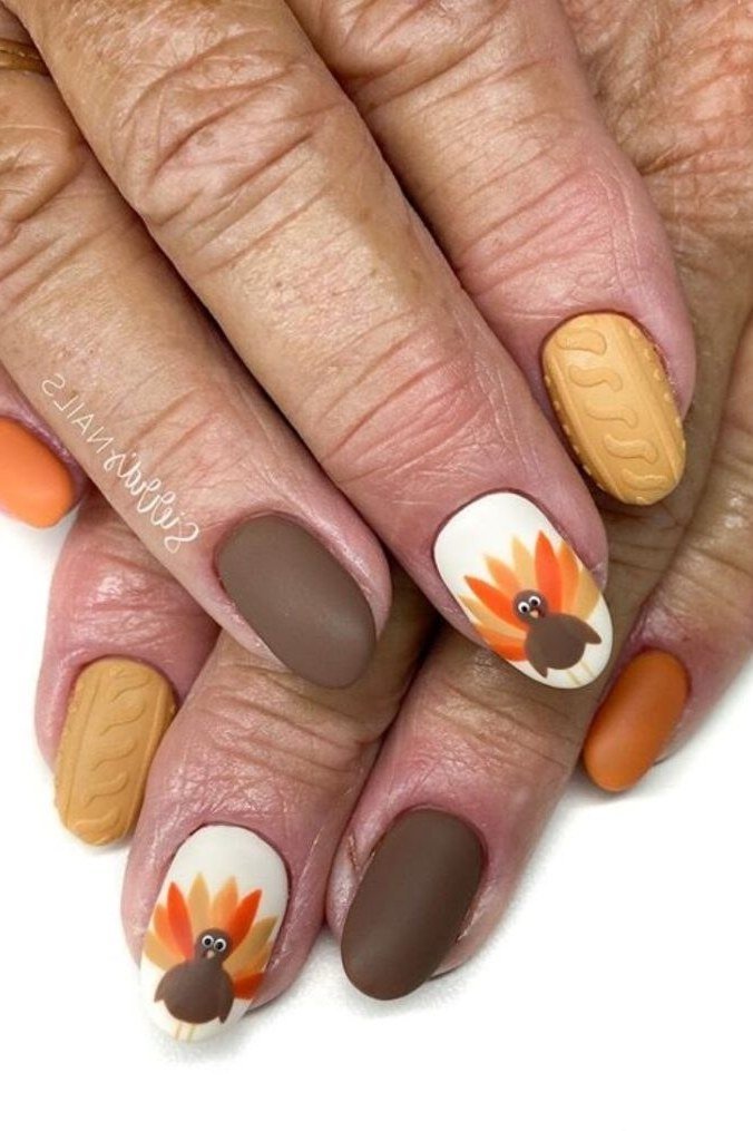 Brown and orange nails with turkey nail art on mature hands