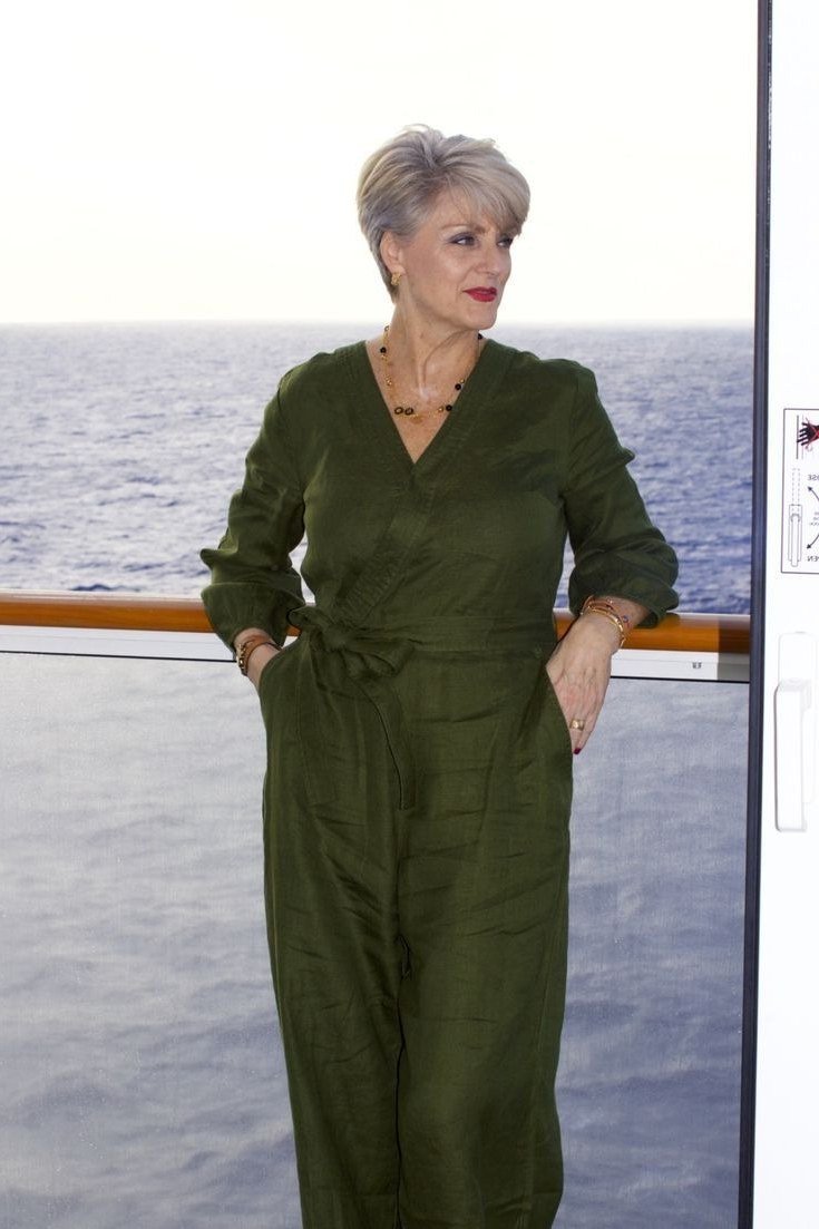 Dark forest green V-neck jumpsuit with a tie waist and three-quarter sleeves, on a cruise ship; rich jewel-tone one-and-done cruise look - travel outfit for women over 50