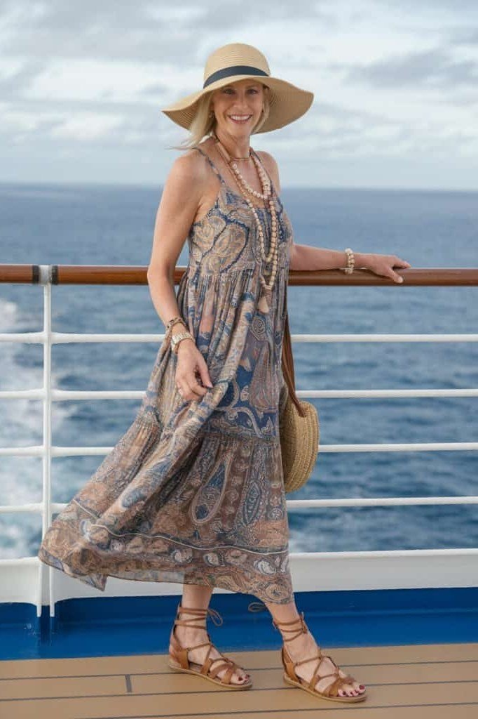 Gray floral maxi dress with a wide straw sun hat and tan sandals, on a cruise ship deck; romantic garden-party cruise outfit - travel outfit for women over 50