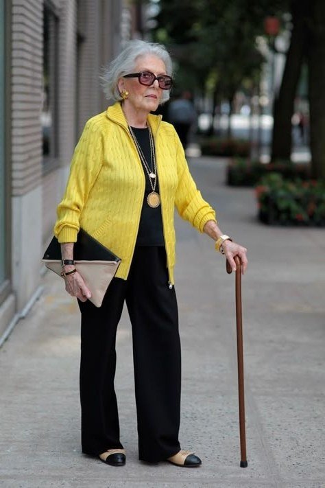 Older woman yellow knit cardigan with black wide pants - trendy outfit idea for women over 70