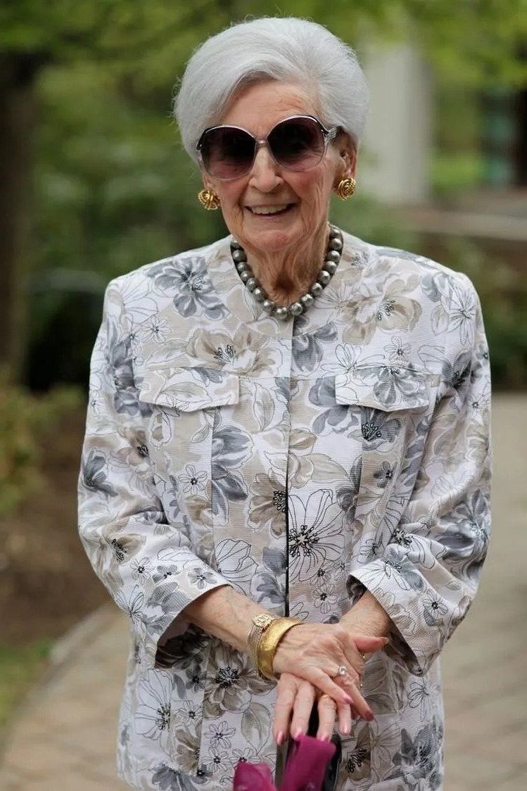 Older woman gray floral print jacket waist up portrait - trendy outfit idea for women over 70