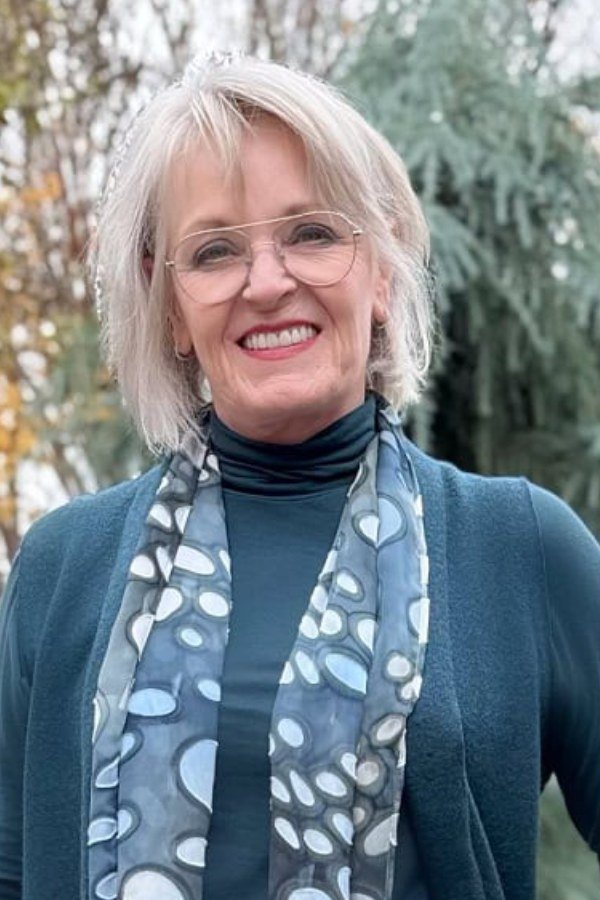 Fall turtleneck outfit for women over 50: teal turtleneck with patterned silk scarf, close-up